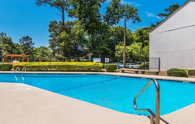 a swimming pool with a building and trees in the background