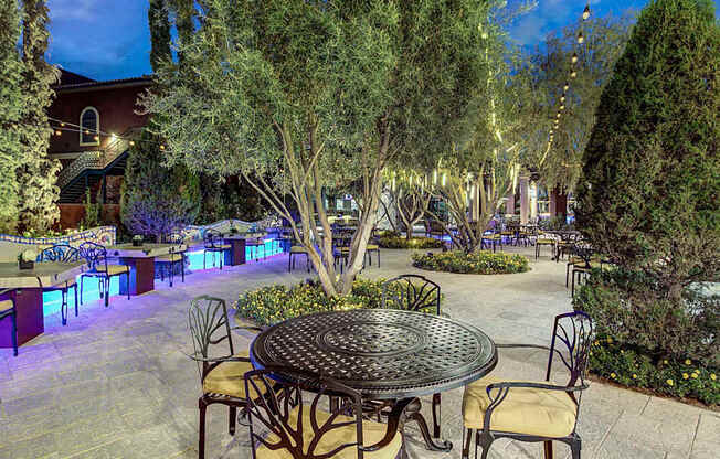 A patio with tables and chairs is lit up with blue lights.