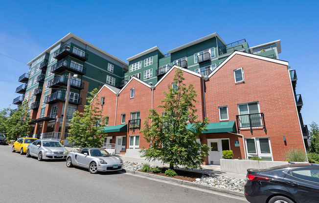 a view from the street of a large apartment complex with cars parked in front of it  at Sedona Apartments, Seattle, WA, 98115