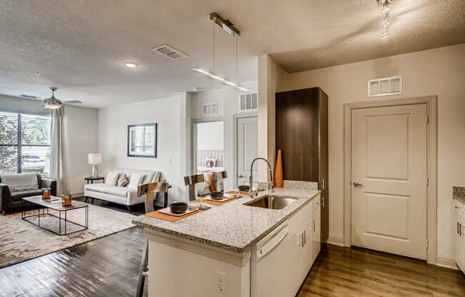 Open-concept kitchen with breakfast bar and view of living area at EOS in Orlando, FL