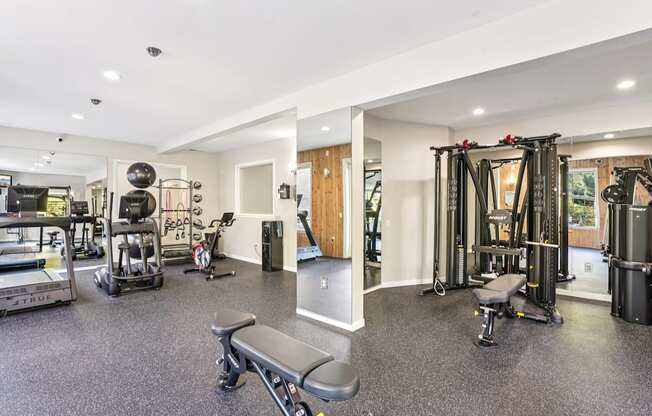 A spacious gym with a variety of equipment including a squat rack, bench, and weights.
