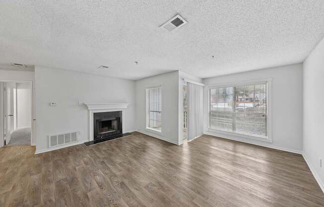 A spacious living room with a fireplace and wood flooring.