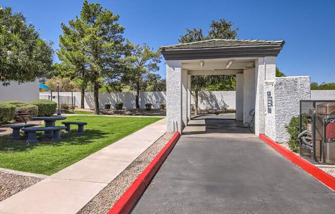 a covered walkway with a picnic table and bench in front of a building