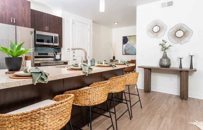 A kitchen with brown wicker chairs and a white counter.