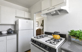 a white kitchen with a stove and a yellow kettle