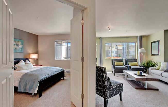 A bedroom with a bed, chair, and a couch. at Mill Creek Meadows Apartments, Mill Creek