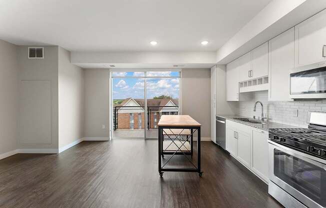 A kitchen with a table and a window overlooking a house.