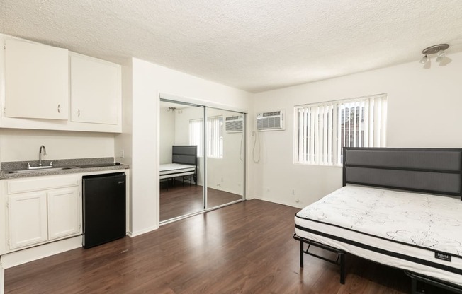 Studio with Hardwood Floors, Mirrored Wardrobe Closet and Kitchen with White Cabinets