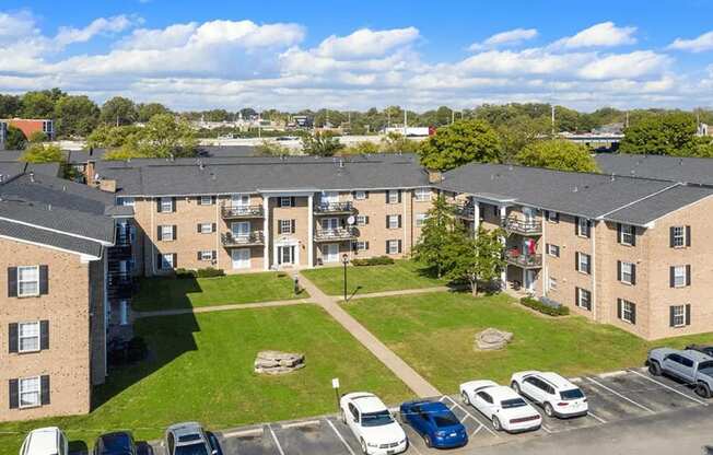 A sunny day at a residential complex with cars parked in the lot.