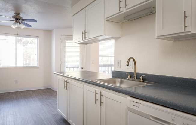 a kitchen with white cabinets and a large window