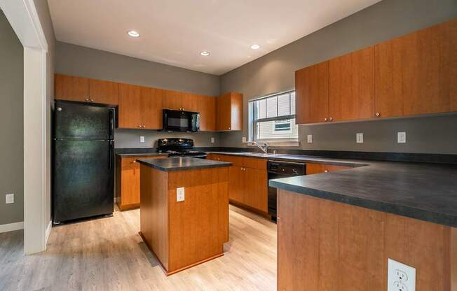 A kitchen with wooden cabinets and a black refrigerator.