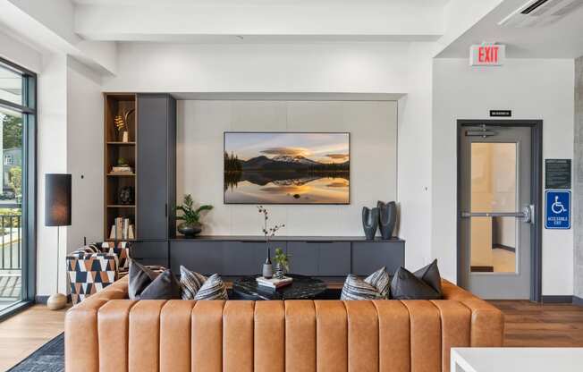 A living room with a brown sofa and a painting on the wall.