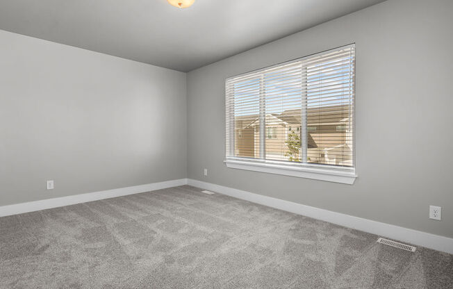 an empty living room with a window and carpet