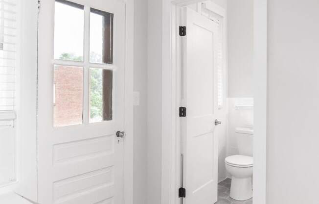 a white bathroom with a white door and a white toilet