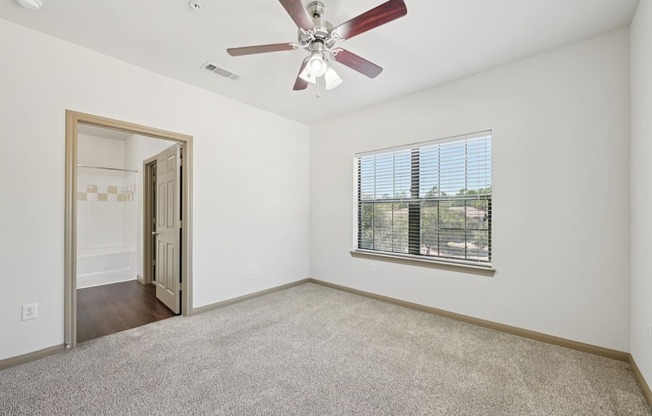 A room with a ceiling fan and a window with blinds.