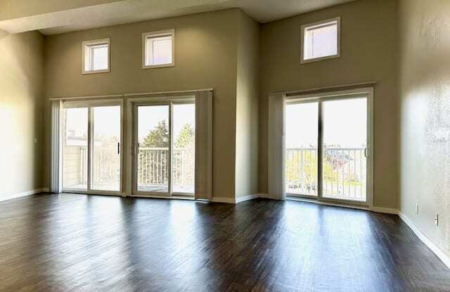 an empty living room with a wood floor and doors