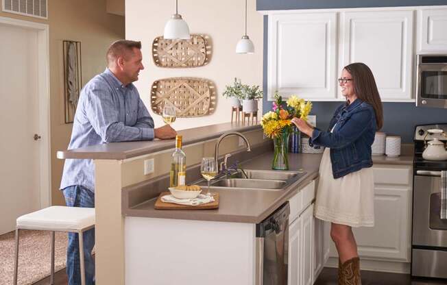 a man and a woman standing at a kitchen island at The Winhall of Williams Pointe Apartments, Waukee