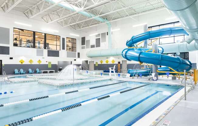 A large indoor swimming pool with a diving board and a slide.