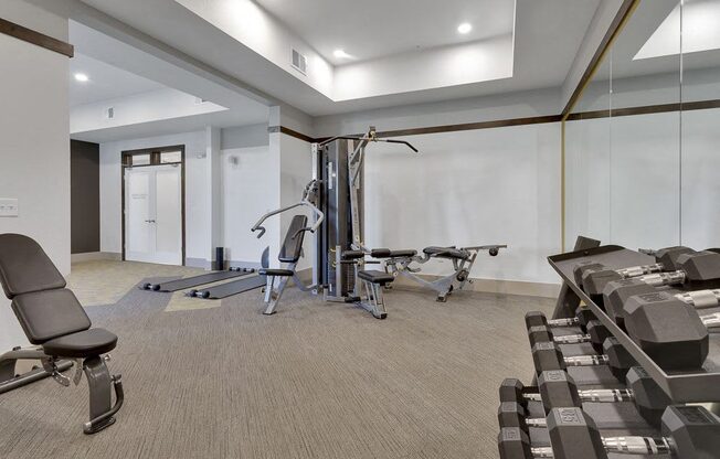A gym with a variety of equipment including weights and a treadmill.