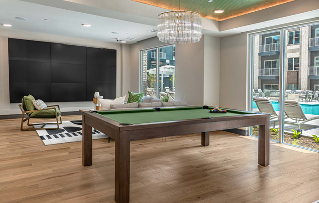 a games room with a pool table and a large window with a view of the pool and