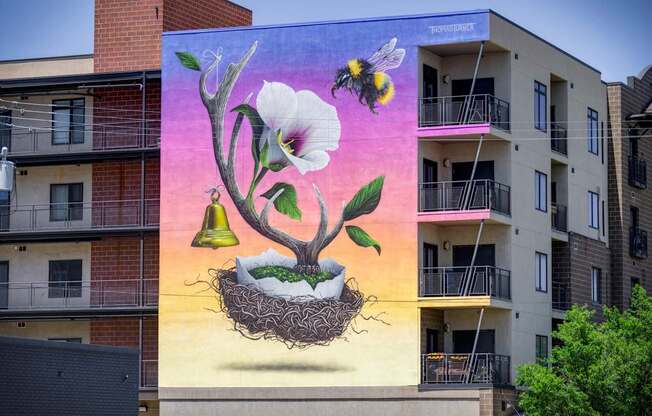 A mural of a flower with a bee and a bell on a building.