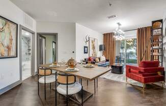 A dining room with a table set for two and a red chair.
