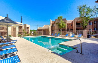 A swimming pool surrounded by blue chairs and a building in the background.