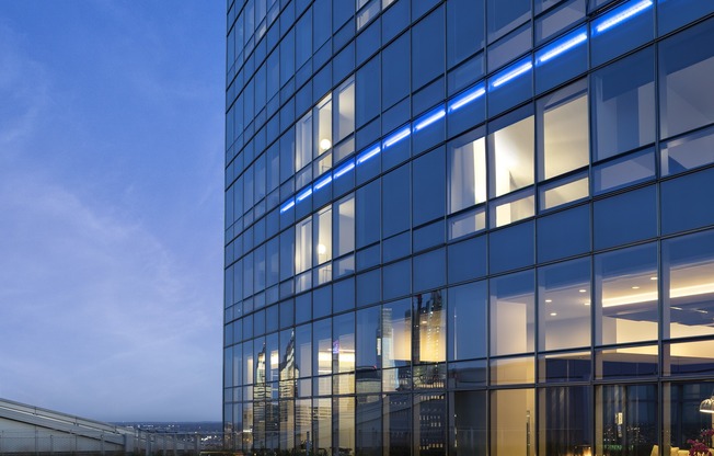 A modern glass building with blue lights reflecting on the windows.