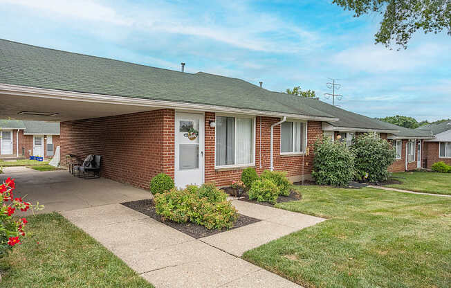 A brick house with a white door and a small garden in front.