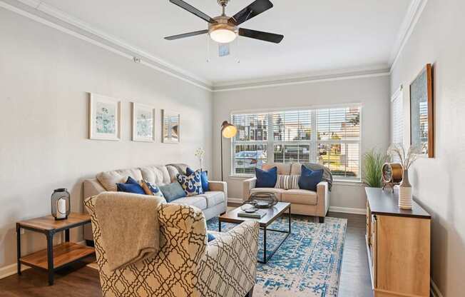 A living room with a couch, chair, and a fan.