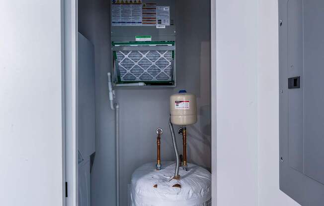 A white refrigerator with a water filter and a water heater in a small room.