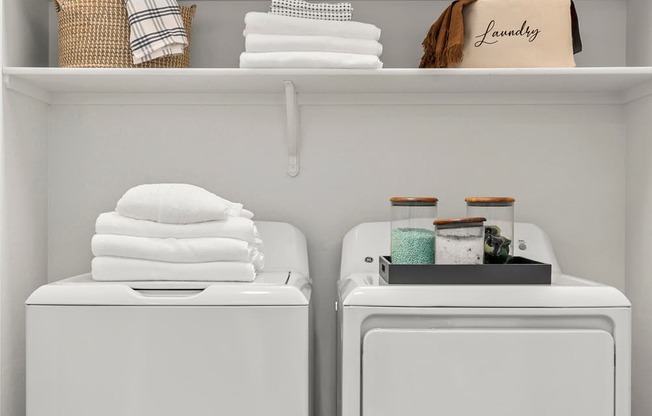 Two white washing machines with towels and baskets on top.