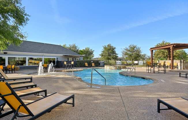 A pool area with a fountain and lounge chairs.