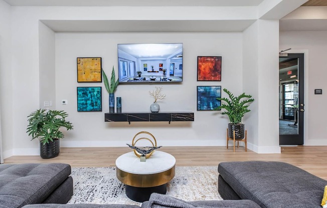 A living room with a grey sofa, a coffee table, and a TV mounted on the wall.