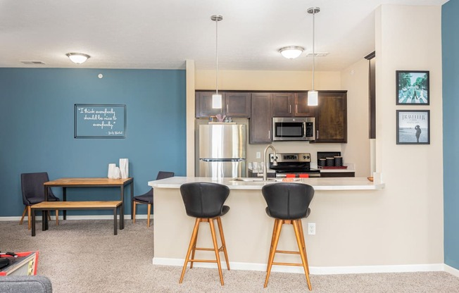 a kitchen with a bar and a living room with a table and chairs