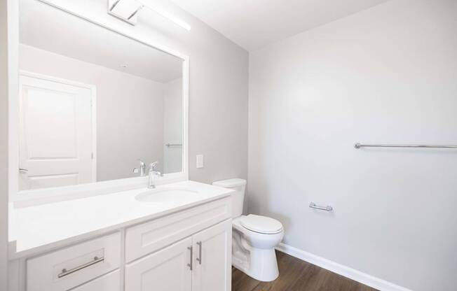 A white bathroom with a toilet, sink, and mirror.