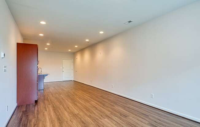 a living room with white walls and wood flooring and a sink