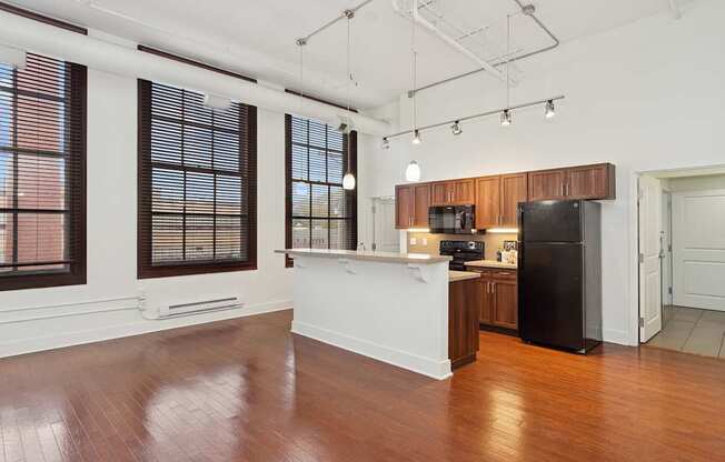A kitchen with a black refrigerator and wooden cabinets.