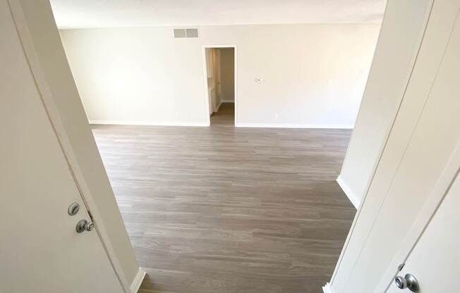 an empty living room with wood floors and white walls