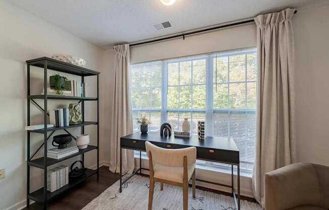 A room with a desk, chair, and a bookshelf.