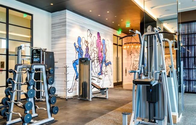 a gym with exercise equipment and a mural on the wall at The Boro, Tysons