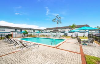 a swimming pool with chairs and umbrellas in front of a building