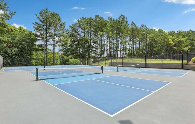 A tennis court surrounded by a fence and trees.