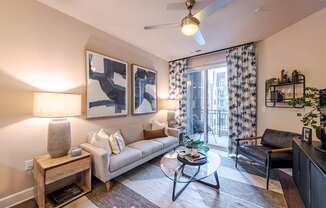 A living room with a couch, a coffee table, and a ceiling fan.