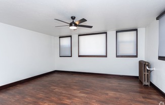 an empty living room with wood floors and a ceiling fan