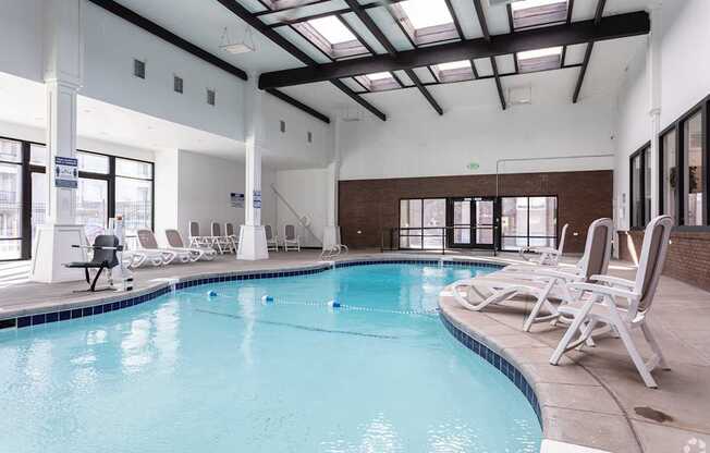 A large indoor swimming pool with lounge chairs and a skylight.