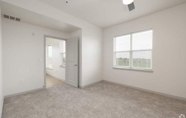 A spacious room with a door, window, and a fan.