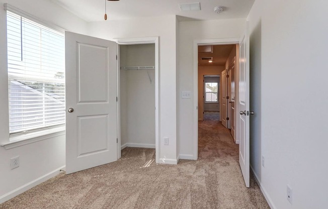 4-BR Townhomes in North Charleston, SC - Highland Townhomes - Empty Bedroom With Carpet Flooring, A Large Window, White Walls, and A Closet