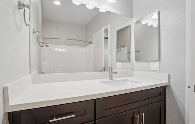 A bathroom with a white sink and brown drawers.
