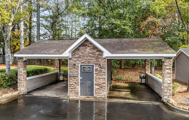 a covered parking lot with a small building with a door